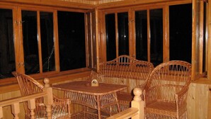 A wooden-paneled room with a dining table and wicker chairs. - Grunyk Guest House (Yaremche)