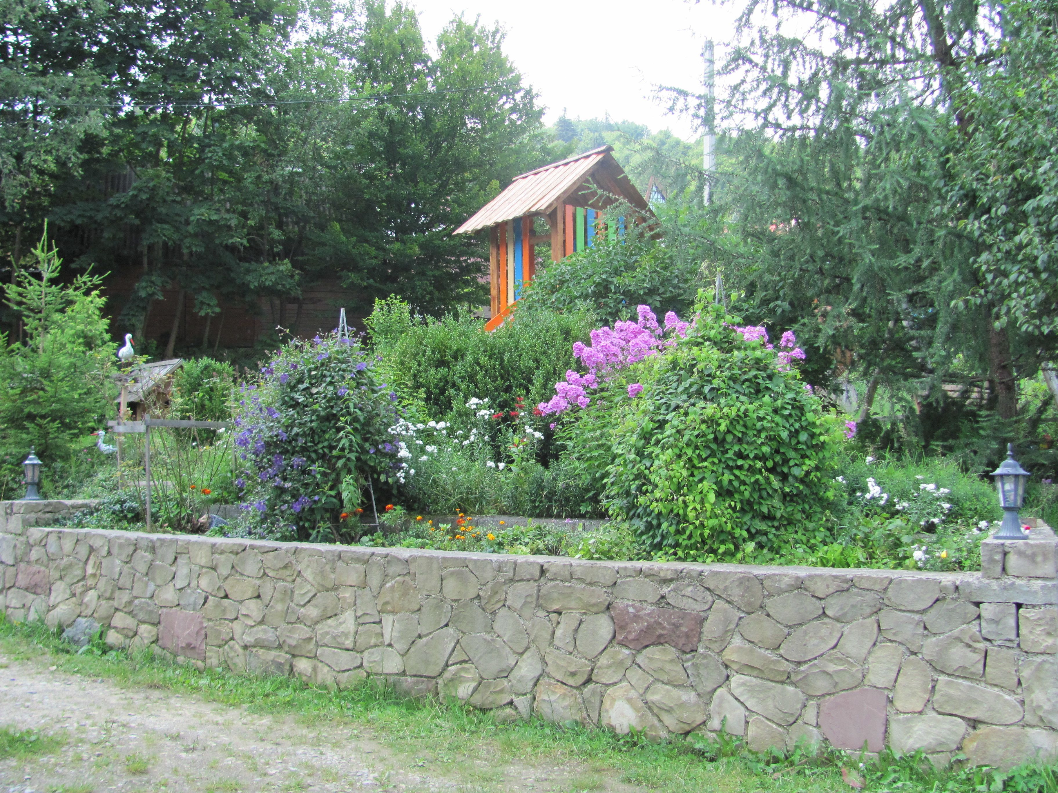 Un mur de pierre avec une structure en bois dans un jardin.