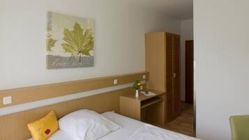 Een hotelkamer met een bed, een nachtkastje met een lamp, een telefoon, een kledingkast en een schilderij aan de muur.