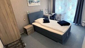 A modern hotel room with a bed, a desk, and a chair. - Hotel Aquarius (Braunschweig)