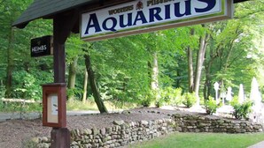 A sign for 'Aquarius' with a wooden structure and stone wall in the background. - Hotel Aquarius (Braunschweig)