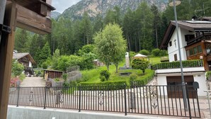 A mountain view with a wooden house and a white building with a balcony.