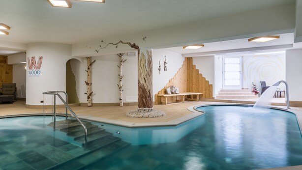An indoor swimming pool with a wooden bench and a staircase leading to a window.