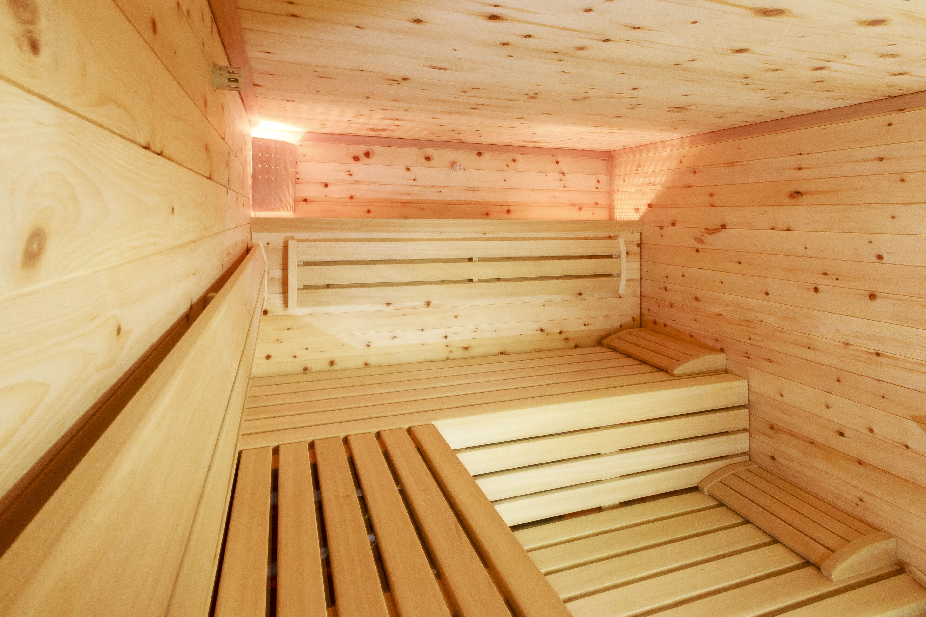 Una sauna de madera con bancos y suelo inclinado.