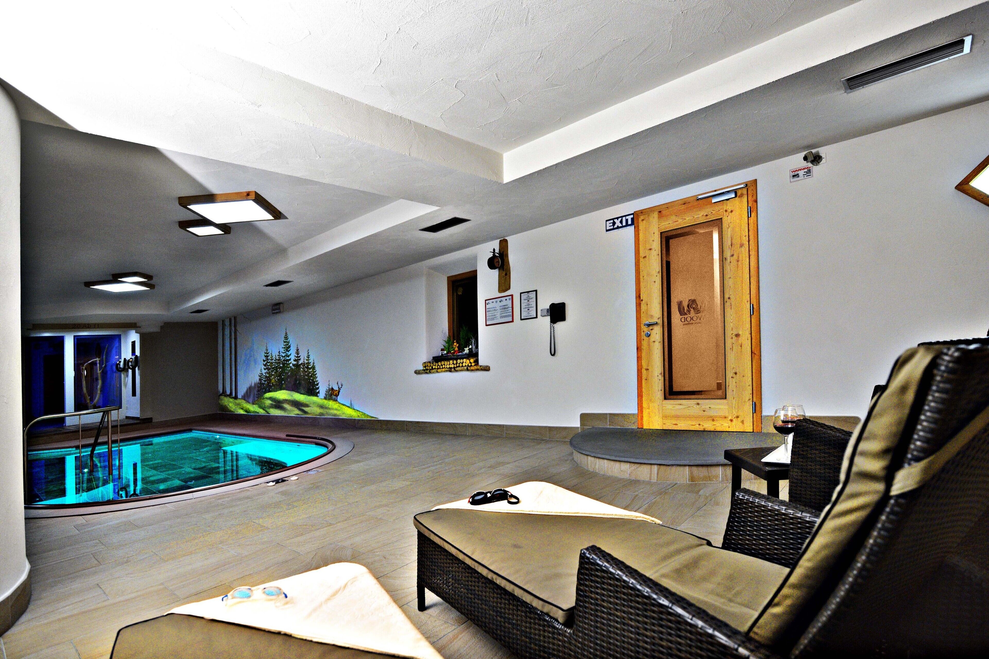 A pool area with a lounge chair, a small table with a glass of wine, and an exit door.