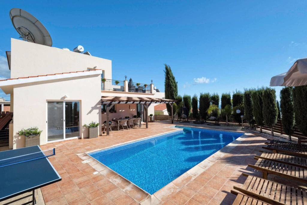 A swimming pool with a sun terrace, outdoor seating, and a satellite dish.