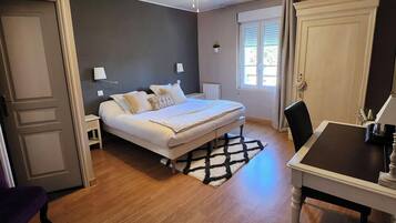 A bedroom with a bed, bedside tables, a ceiling fan, a window with curtains, and a wooden floor.