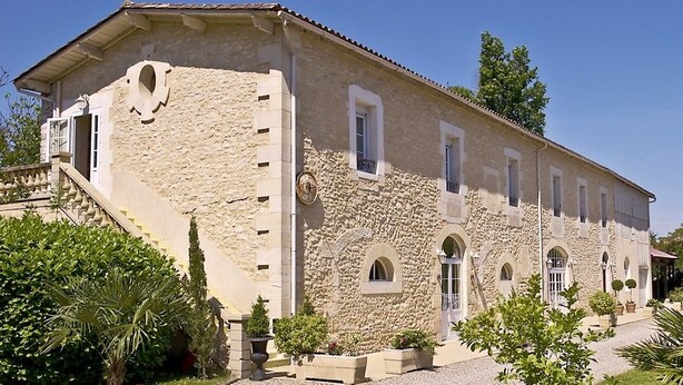 A stone building with a staircase, arched windows, and a garden with potted plants. - Hôtel la Tour Perrier (Eyrans)
