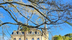 A bicycle parked on a gravel path with a large, historic building in the background. - Hôtel la Tour Perrier (Eyrans)