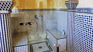 A bathroom with a tiled floor, a shower area, and a decorative archway. - Hôtel la Tour Perrier (Eyrans)