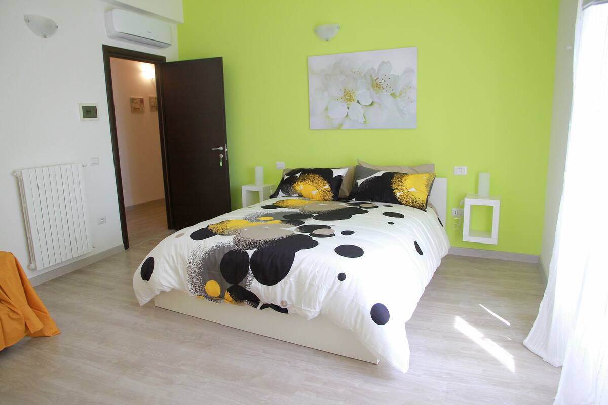 Un dormitorio con cama, un radiador, una puerta y una pared con una pintura de flores.
