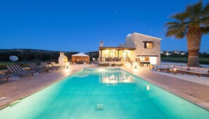 Une maison à deux étages avec une piscine, un espace salon extérieur et une antenne parabolique.