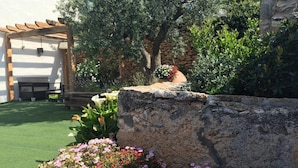 Un jardín con una pérgola, un muro de piedra y una variedad de flores.