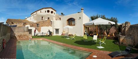 Una piscina al aire libre, sombrillas, sillones reclinables de piscina