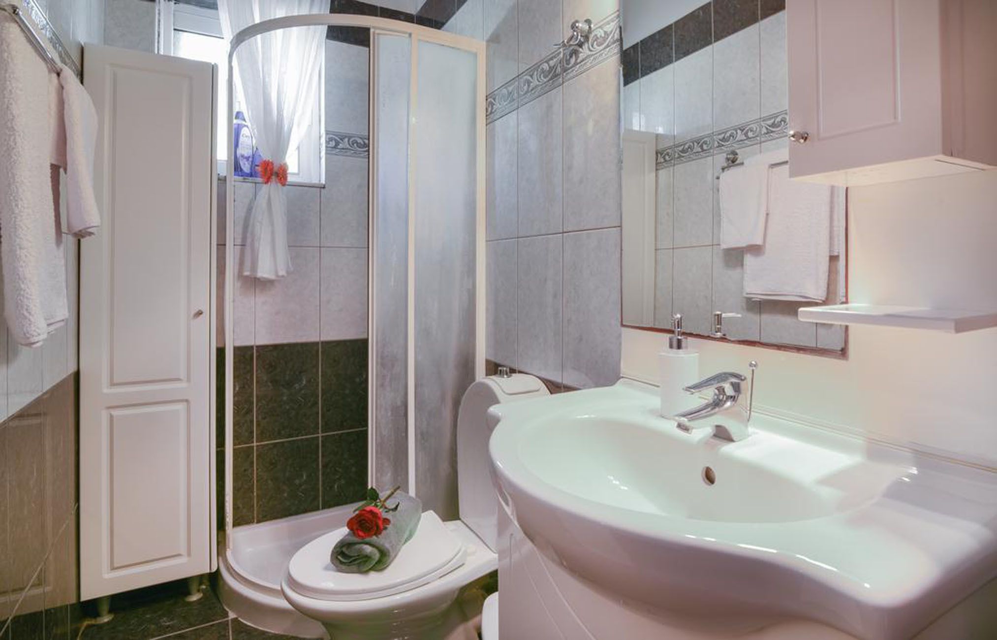 Ein Badezimmer mit einem weißen Waschbecken, einer Toilette und einer Duschkabine.