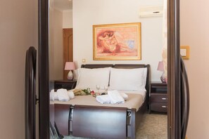 Un lit bien fait, avec du linge de lit blanc, deux tables de chevet avec des lampes et un tableau au mur.