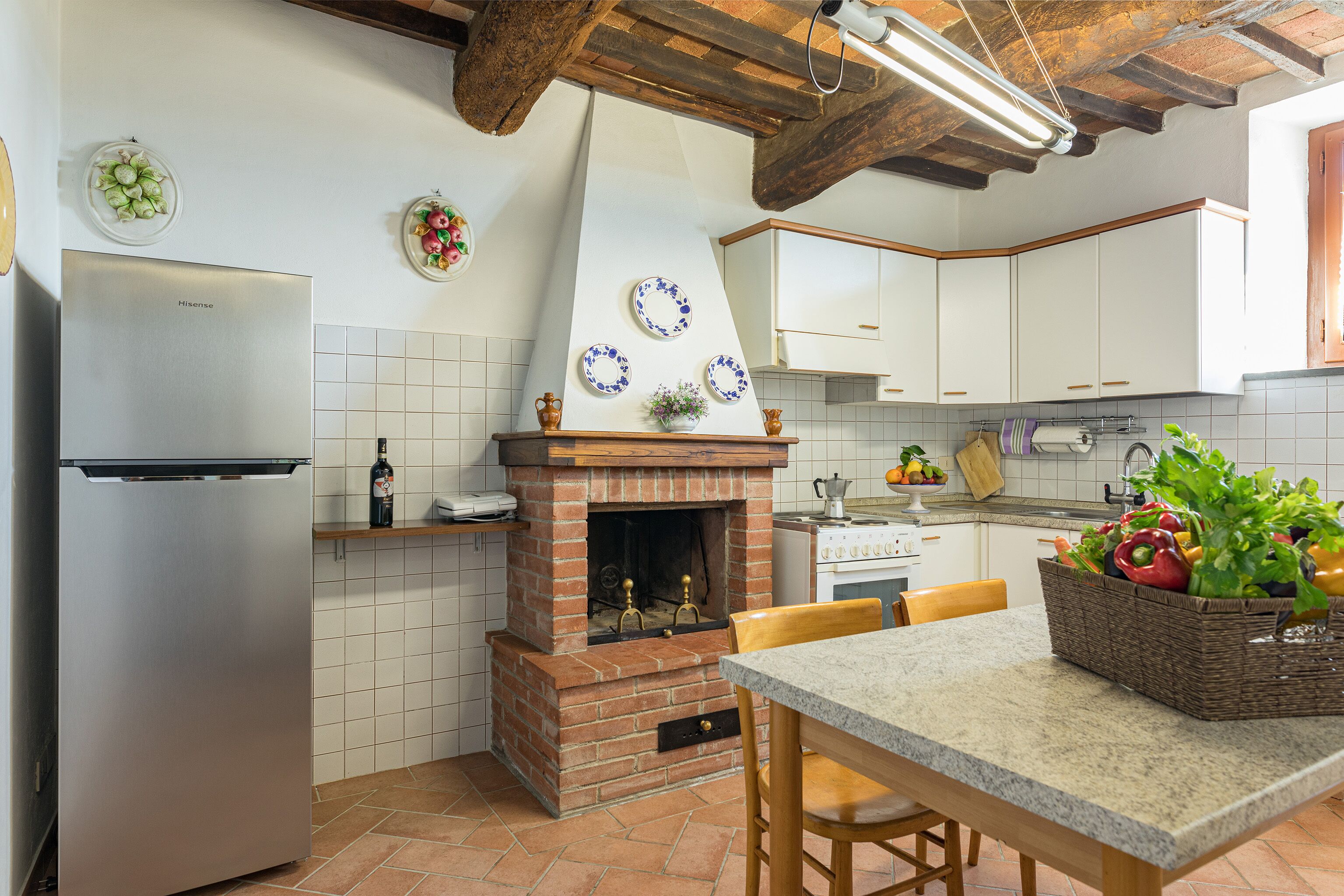 A kitchen with a brick fireplace, white cabinets, and a granite countertop.