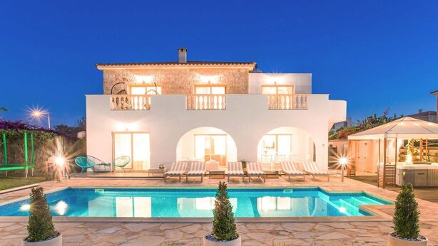 A two-story house with a swimming pool, outdoor seating, and a well-lit balcony. - Villa Jaimi (Pegeia)