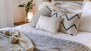 A neatly made bed with a quilted cover, several pillows, and a knitted blanket. - Villa Jaimi (Pegeia)