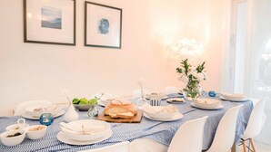A dining table set with plates, bowls, and a vase of flowers, with two framed pictures on the wall. - Villa Jaimi (Pegeia)