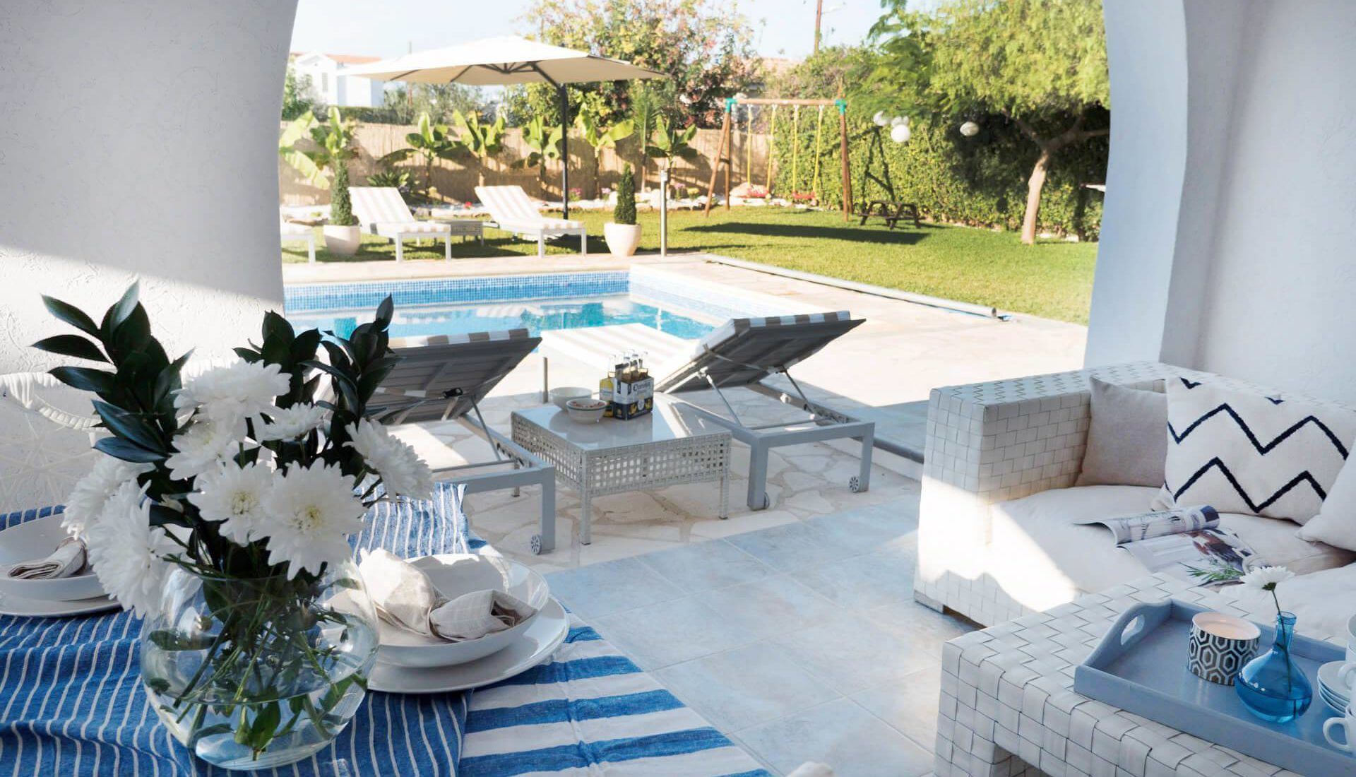 Un espace aménagé au bord de la piscine, avec des chaises longues, une table avec des boissons et un canapé.