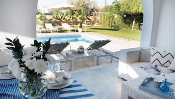 Un espace aménagé au bord de la piscine, avec des chaises longues, une table avec des boissons et un canapé.