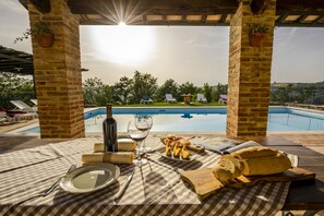 A table set for a meal with a view of a swimming pool and a sunset. - Agriturismo La Coppa (Asciano)