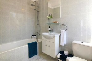 A modern bathroom with a bathtub, a sink, and a toilet. - Villa Searay (Paphos)