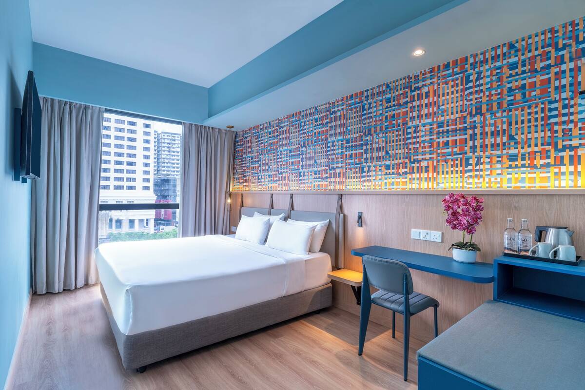 Una habitación de hotel moderna con una cama grande, un escritorio y vistas a la ciudad.
