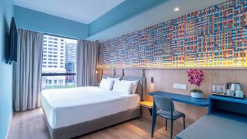 A modern hotel room with a large bed, a desk, and a view of the city.