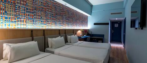 Habitación de hotel con dos camas, un escritorio y una obra de arte grande en la pared.