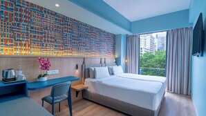 A modern hotel room with a large bed, a desk with a chair, a small table with a plant, and a view of the city through a large window. - Ibis Styles Kuala Lumpur Bukit Bintang (Kuala Lumpur)