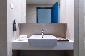 A modern bathroom with a white sink, a mirror above it, and a blue door in the background. - Ibis Styles Kuala Lumpur Bukit Bintang (Kuala Lumpur)