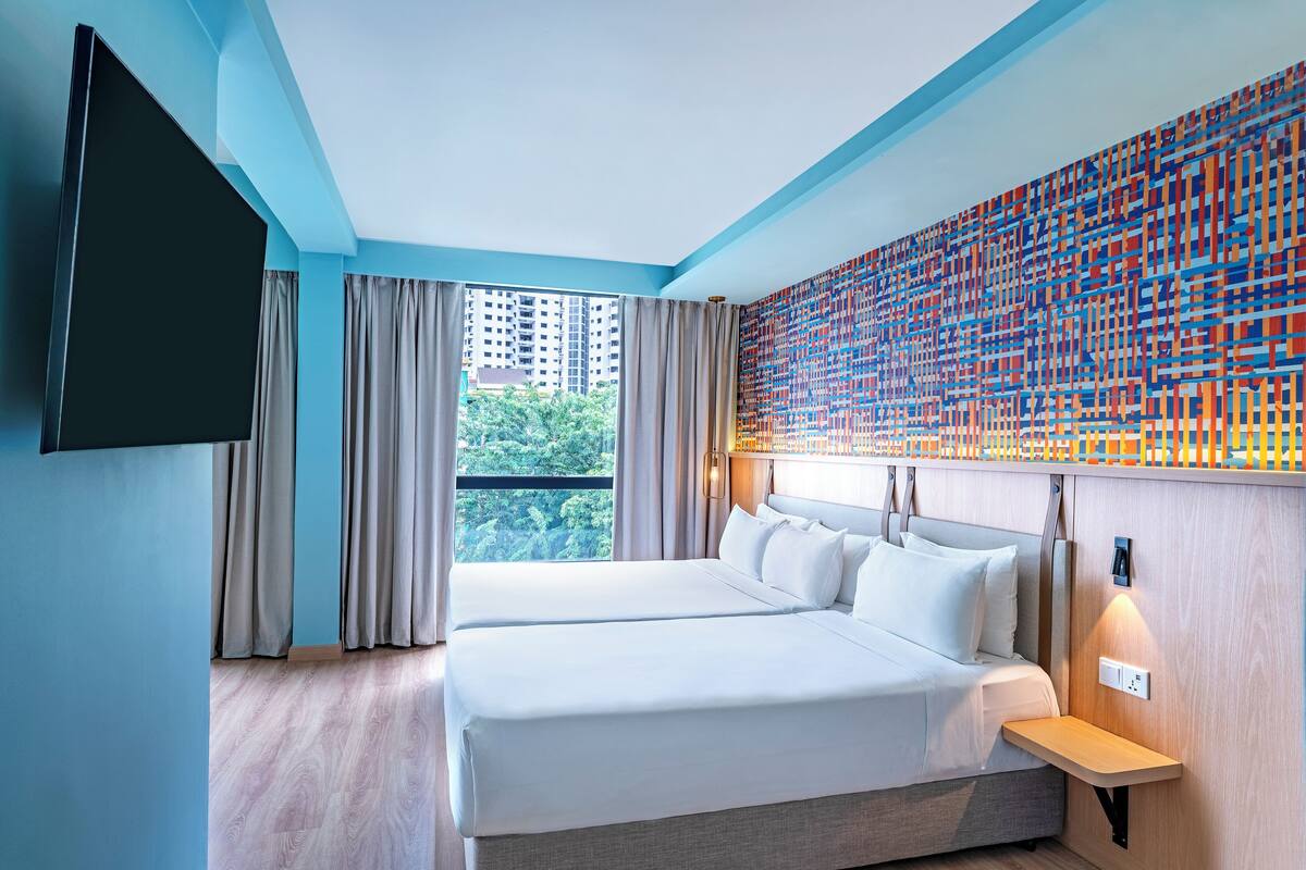 Una habitación de hotel moderna con una cama grande, un televisor y vistas a la ciudad.