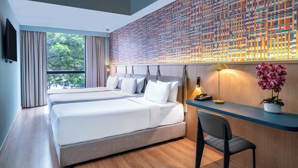 A modern hotel room with a large bed, a desk, and a view of greenery through the window. - Ibis Styles Kuala Lumpur Bukit Bintang (Kuala Lumpur)