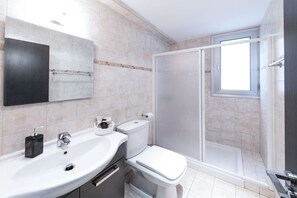 A modern bathroom with a sink, toilet, and glass-enclosed shower.