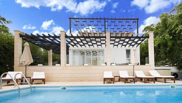 Un espace piscine doté de chaises longues et d’une structure en forme de pergola.
