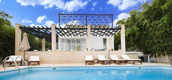 Alberca al aire libre y camastros 