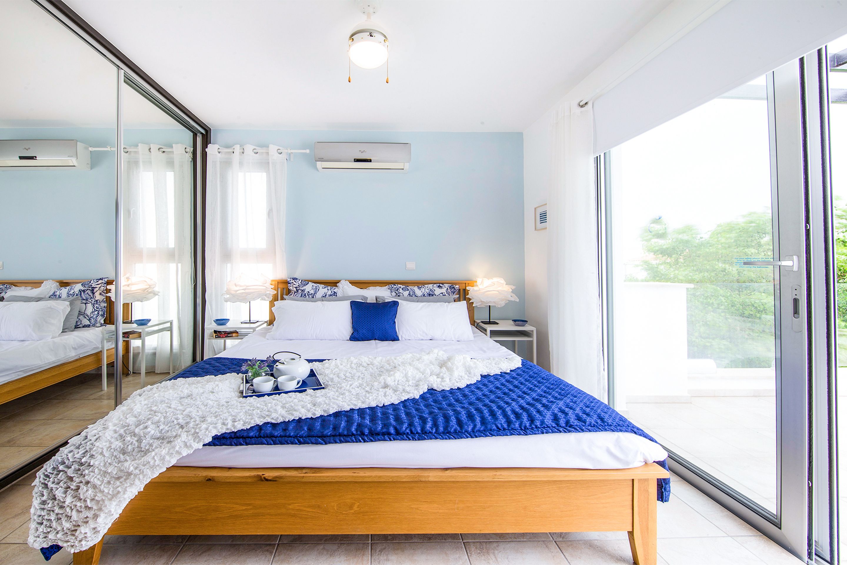 Un dormitorio moderno con una cama grande, una mesita de noche y una puerta de cristal corrediza al exterior.