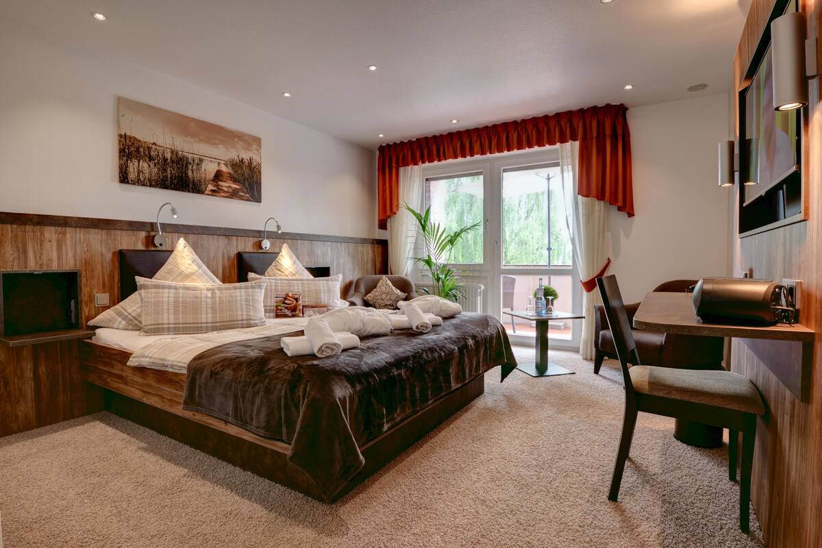 A modern hotel room with a large bed, a desk, and a TV.