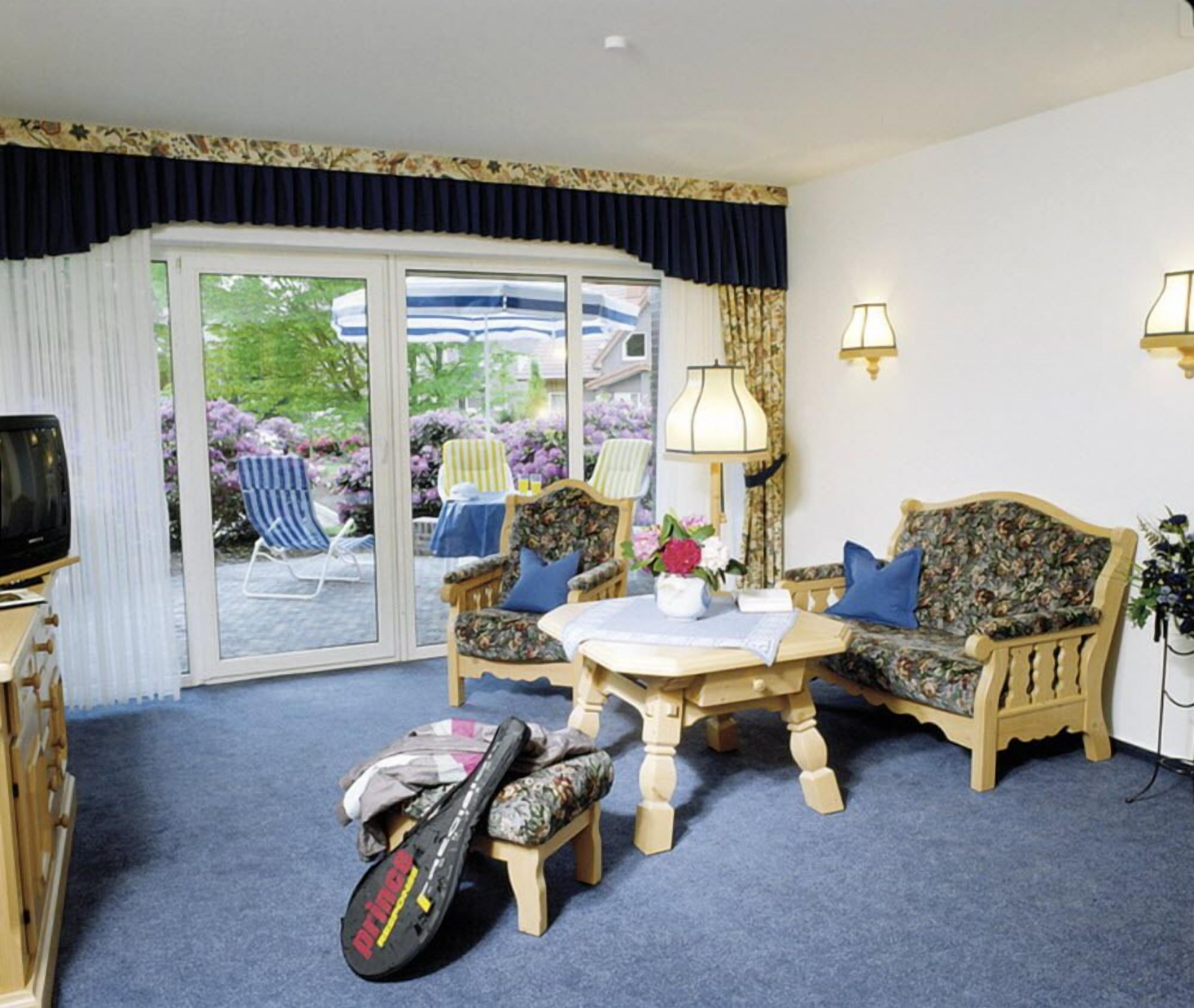 A room with a sofa, armchairs, a table, and a television.