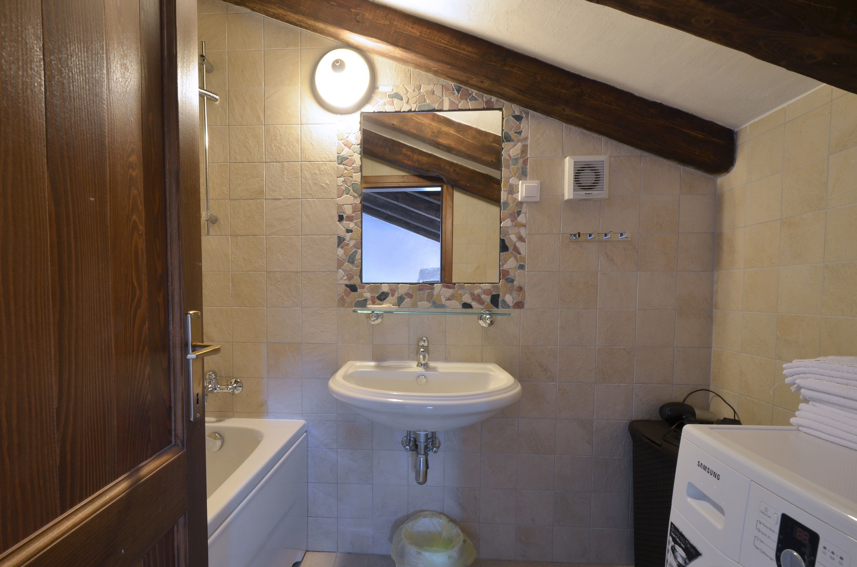 Un bagno con lavandino bianco, specchio, doccia e lavatrice.