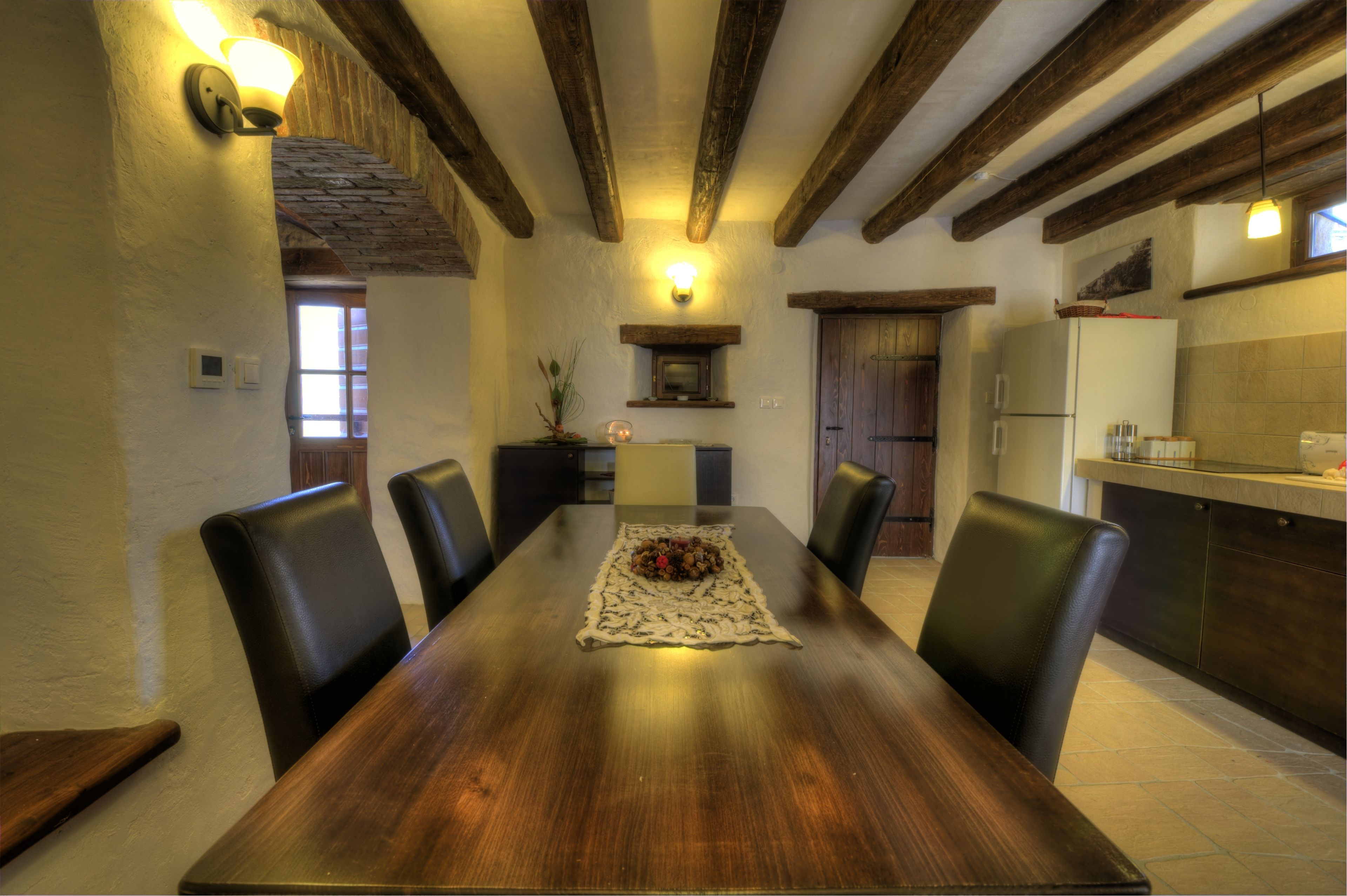 Un comedor con una mesa de madera, sillas negras y un centro de mesa decorativo.