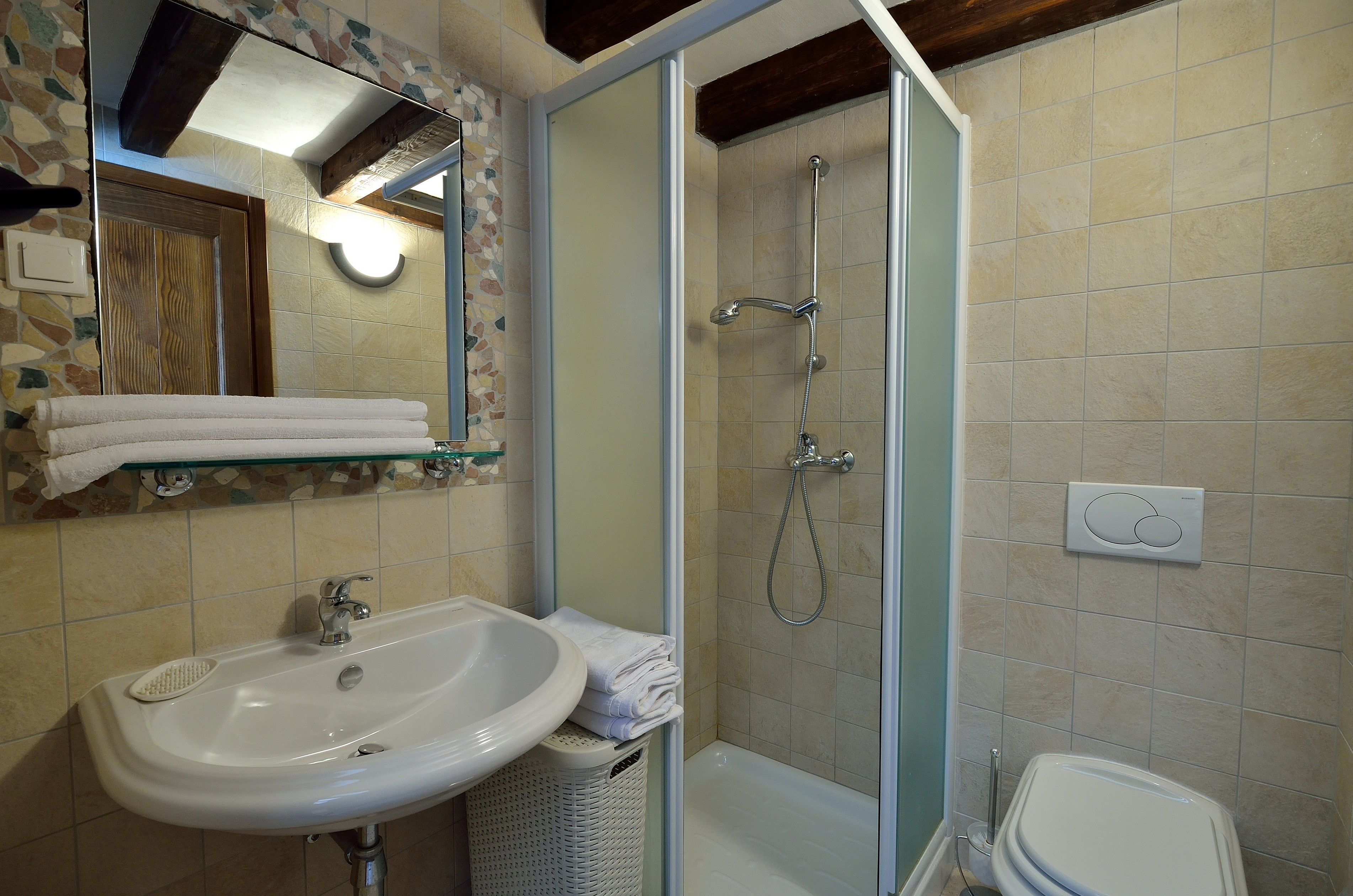 Un baño con lavamanos, espejo, ducha e inodoro.