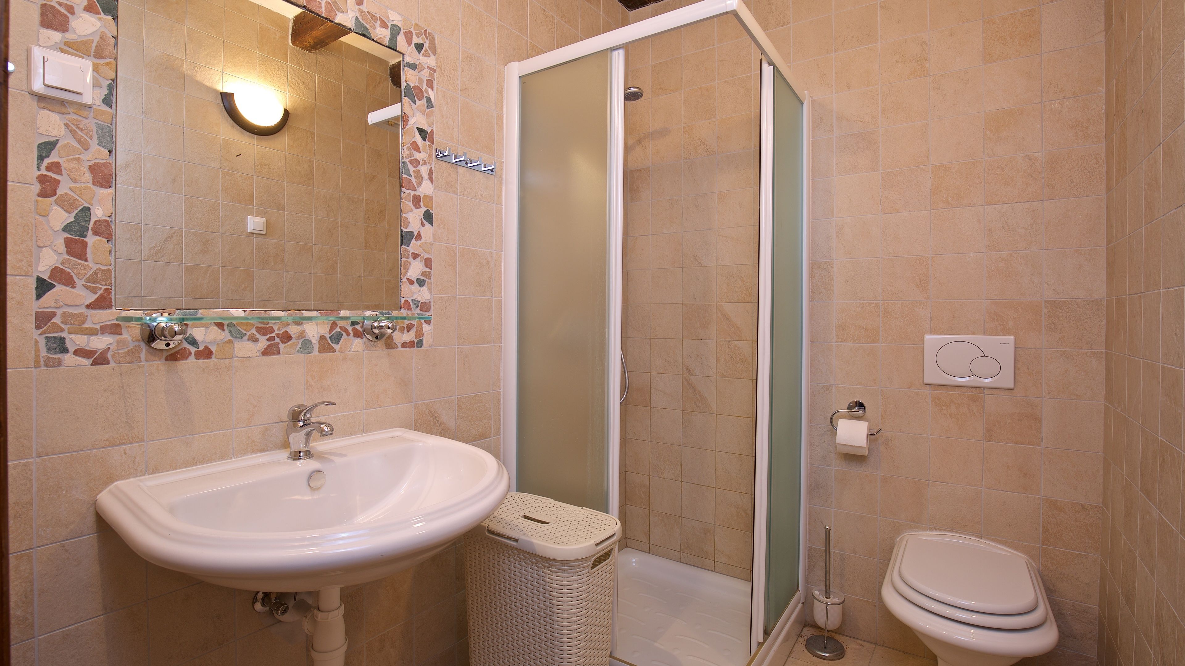 Ein Badezimmer mit Waschbecken, Spiegel, Dusche, Toilette und Mülleimer.
