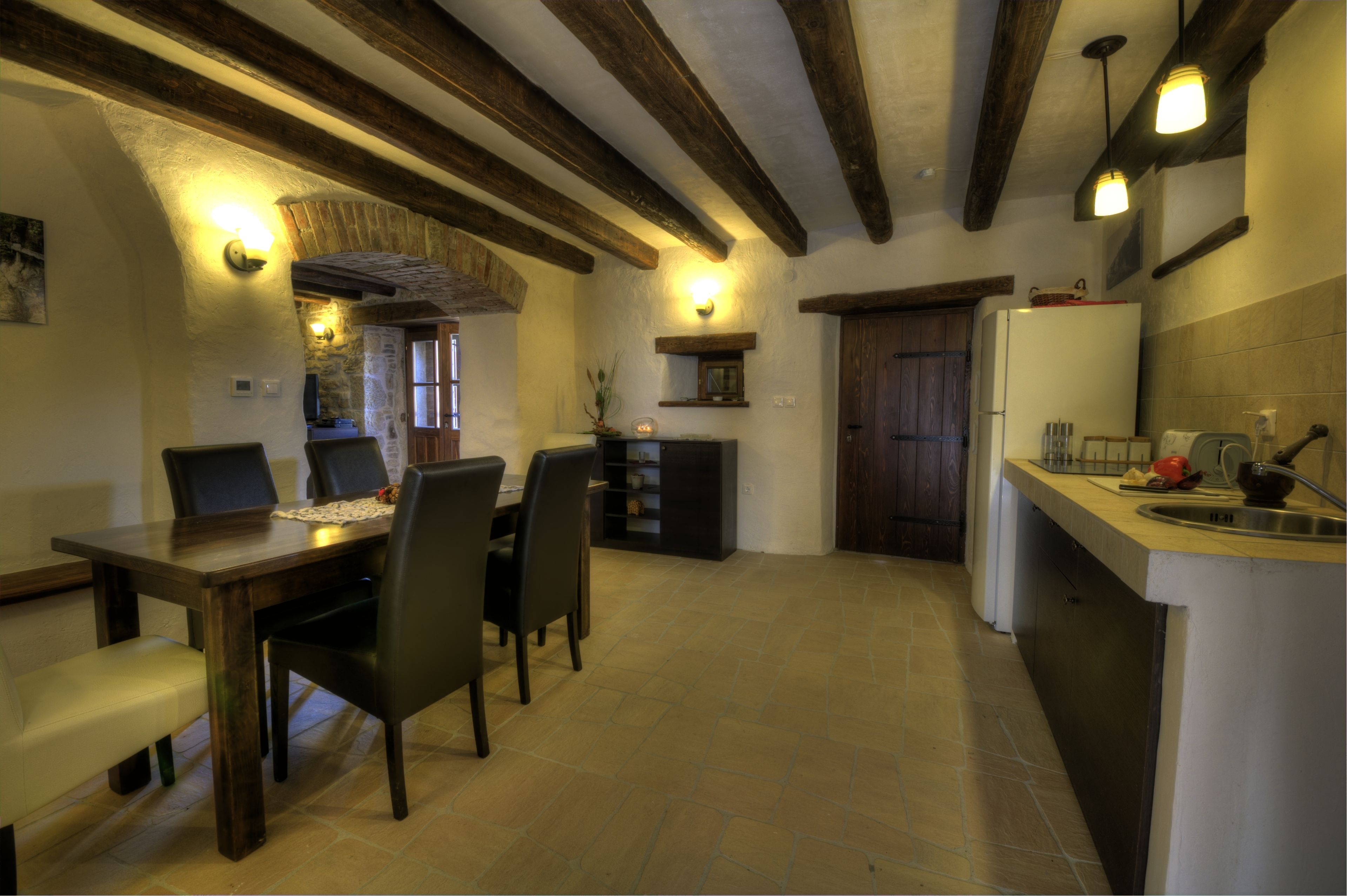A kitchen with a dining table, chairs, a refrigerator, and a sink.