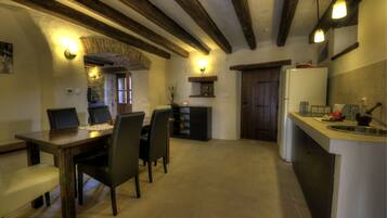 A kitchen with a dining table, chairs, a refrigerator, and a sink.