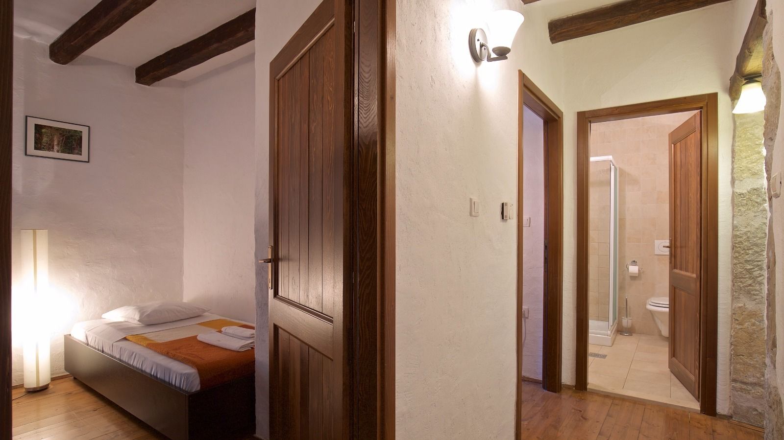 Une chambre à coucher avec un lit, une lampe de chevet et une porte donnant sur une salle de bain.