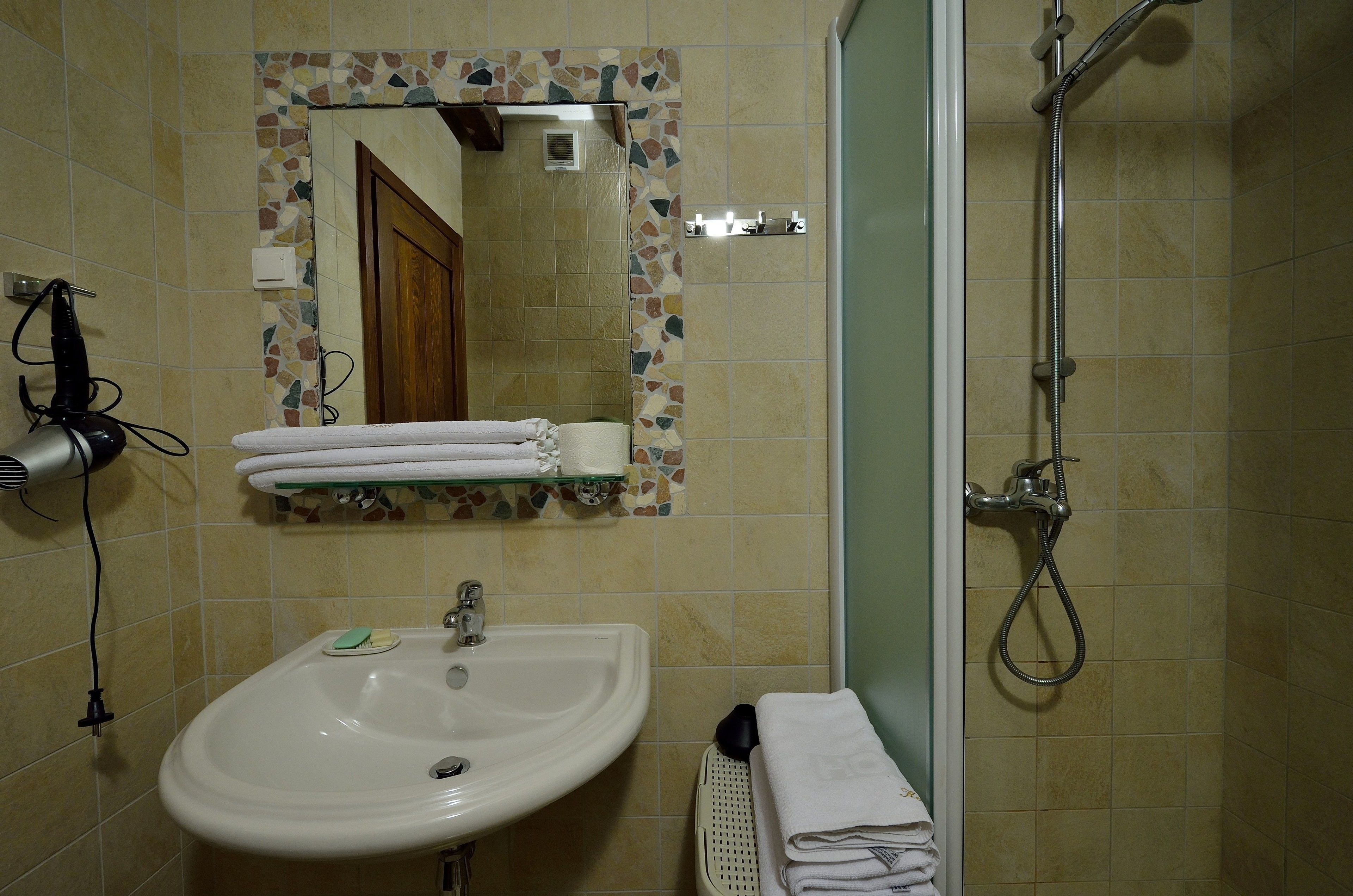 Ein Badezimmer mit Waschbecken, Spiegel, Dusche und Handtüchern.