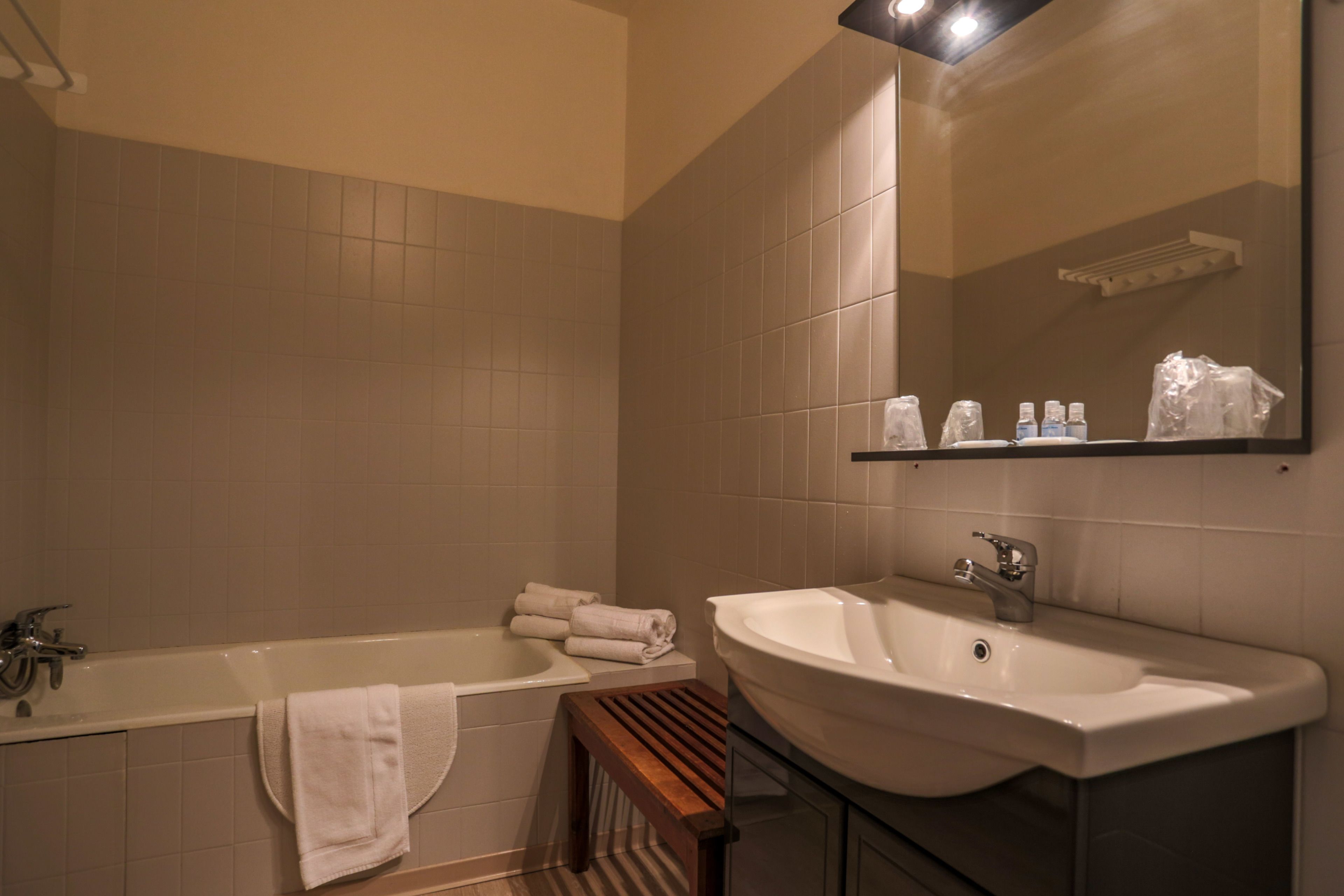 A bathroom with a bathtub, a sink, and a mirror.